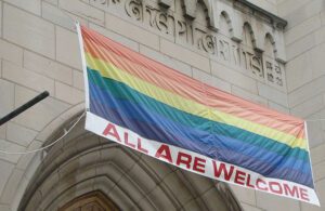 A rainbow flag hangs on the side of a building.