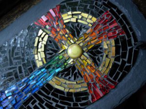 A rainbow mosaic cross on a black background.