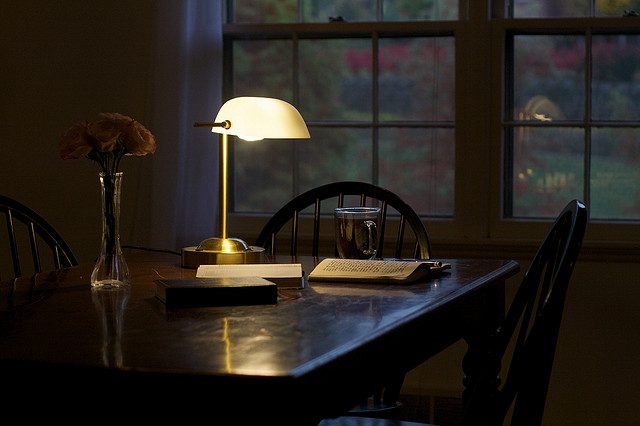 A lamp on a table next to a window.