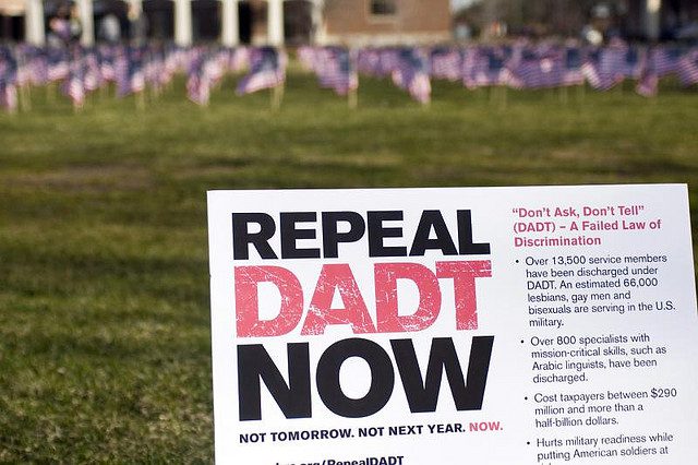 A sign that says repeal dad now in front of flags.