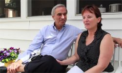A man and woman sitting on a white porch.