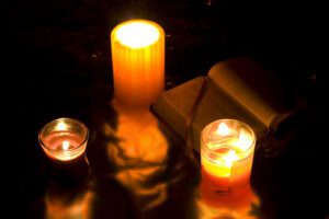 Three candles and an open book on a dark surface.