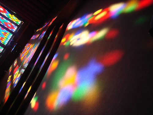 Colorful stained glass light reflecting on wall