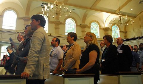 Congregation standing in sunlit historic chapel