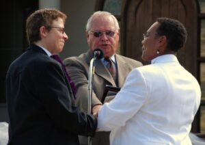 A man and woman shake hands in front of a microphone.