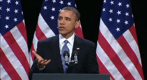 Man speaking at podium with U.S. flags