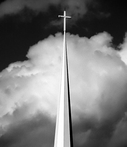 Tall steeple and cross against dramatic clouds