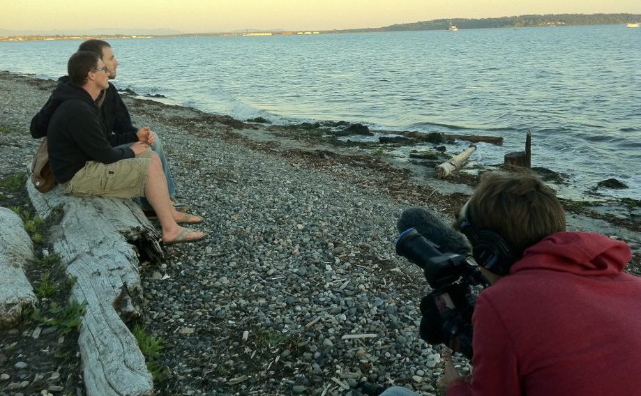 A group of people sitting on a beach with a camera.