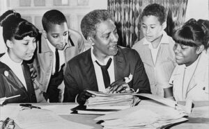 A group of people sitting around a desk looking at papers.