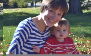 A woman holding a baby in a park.