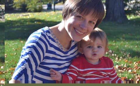 A woman holding a baby in a park.