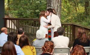 A couple kisses in front of a crowd of people.