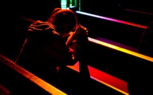 A woman praying in a dark church.