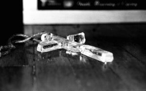 A black and white photo of a cross on a wooden floor.