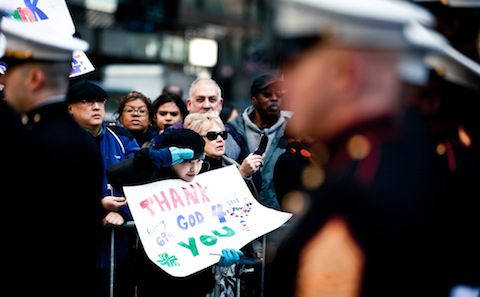 A group of people holding signs in front of a group of marines.