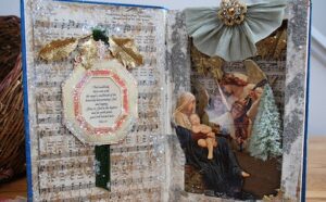 An open book with a christmas scene and ornaments.