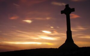A cross is silhouetted against a sunset.