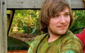 A man and a woman sitting on a wooden deck.