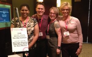 A group of people posing for a photo with a sign.