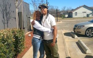 A man and woman hugging in front of a parking lot.