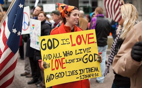 A woman holding a sign that says god is love.