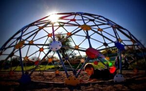 A boy is playing in a playground with a large dome.