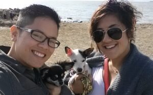 A man and woman pose for a selfie with their dogs.