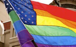 A rainbow flag flies in front of a building.