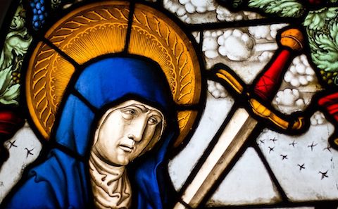 A stained glass window with a woman holding a sword.