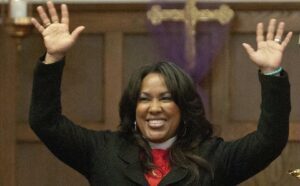 A woman waving her hands in front of a church.
