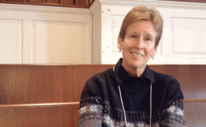 A woman sitting on a wooden bench in a church.