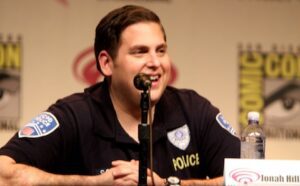 A man in a blue shirt is smiling at a microphone.