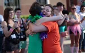 A man and woman hugging in front of a crowd.