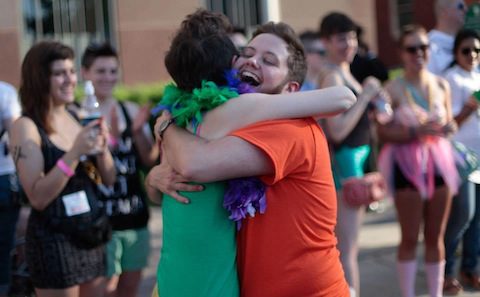 A man and woman hugging in front of a crowd.