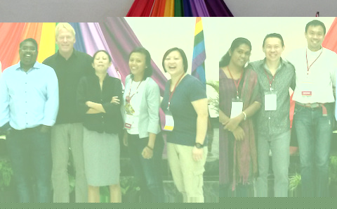 A group of people standing in front of a rainbow flag.