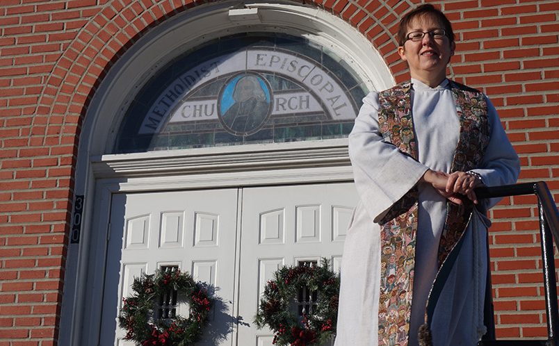 A woman in a white robe standing in front of a church.