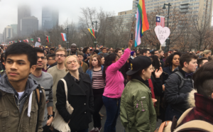 Crowd marching with flags and signs outdoors.