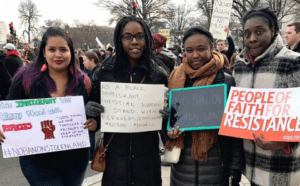 A group of people holding signs with the words people of faith for resistance.
