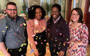Four people celebrating with colorful confetti.