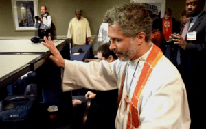A priest is standing in front of a group of people.