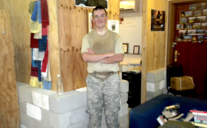 Person standing in casual military attire indoors.