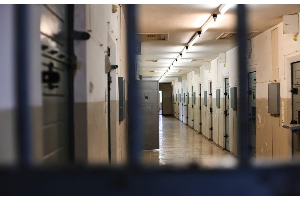 A view of a prison cell with bars on the door.