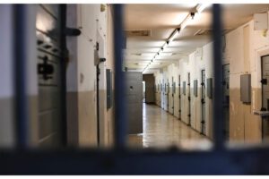 A view of a prison cell with bars on the door.